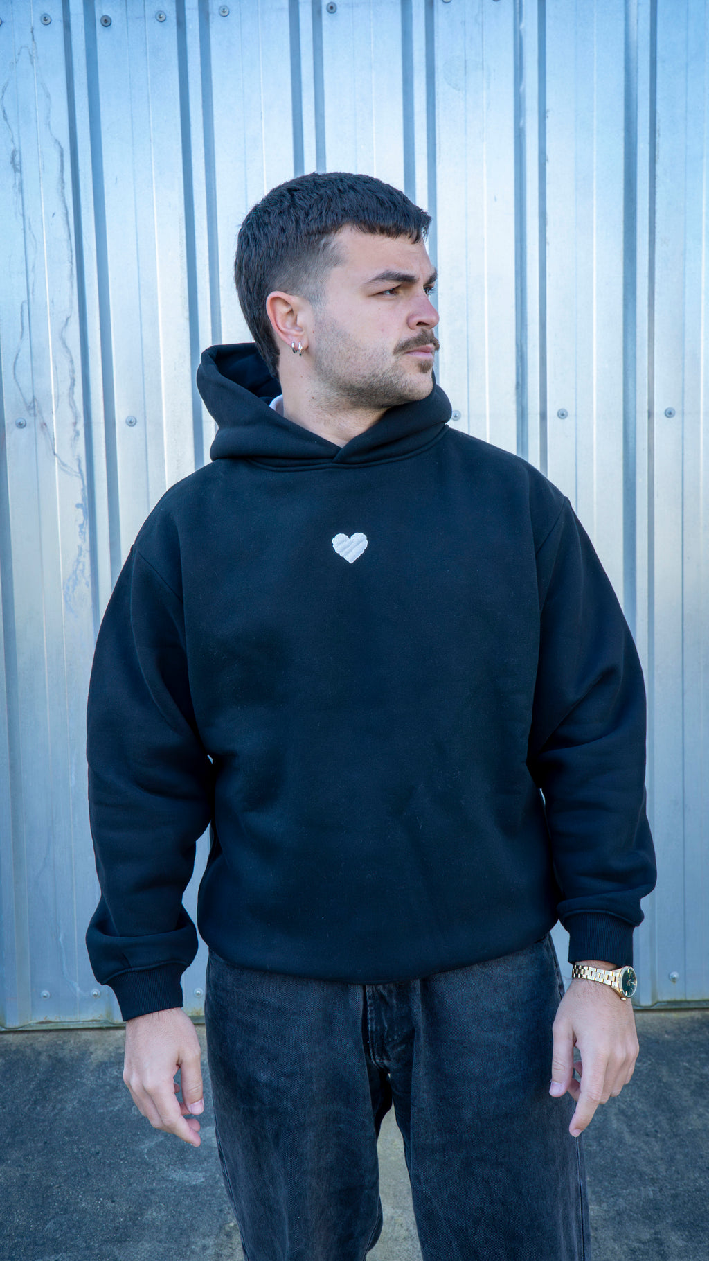 Modelo con sudadera negra oversize estilo streetwear y corte drop shoulder.